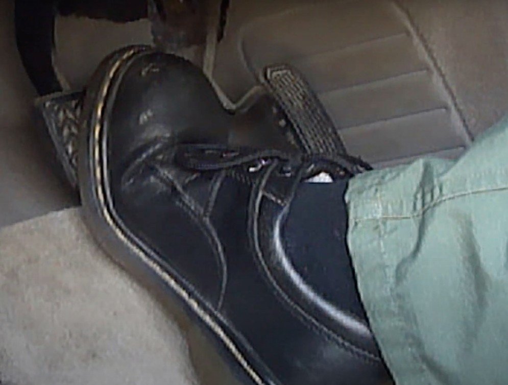 Photo of foot pressing down on brake pedal that goes to the floorboard, indicating brake servicing is needed.